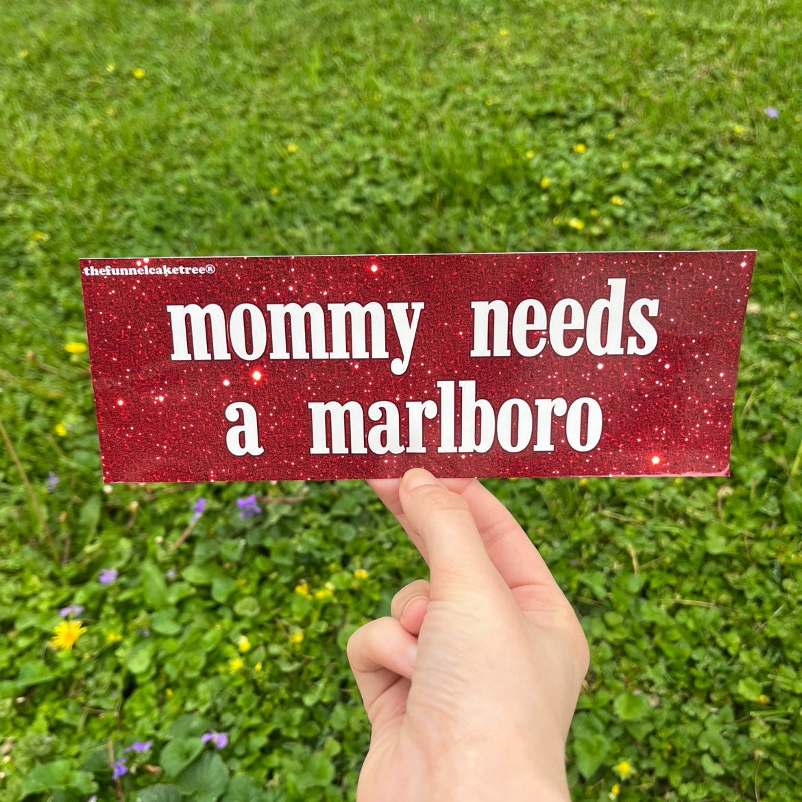 Red bumper sticker with white text reading Mommy needs a marlboro