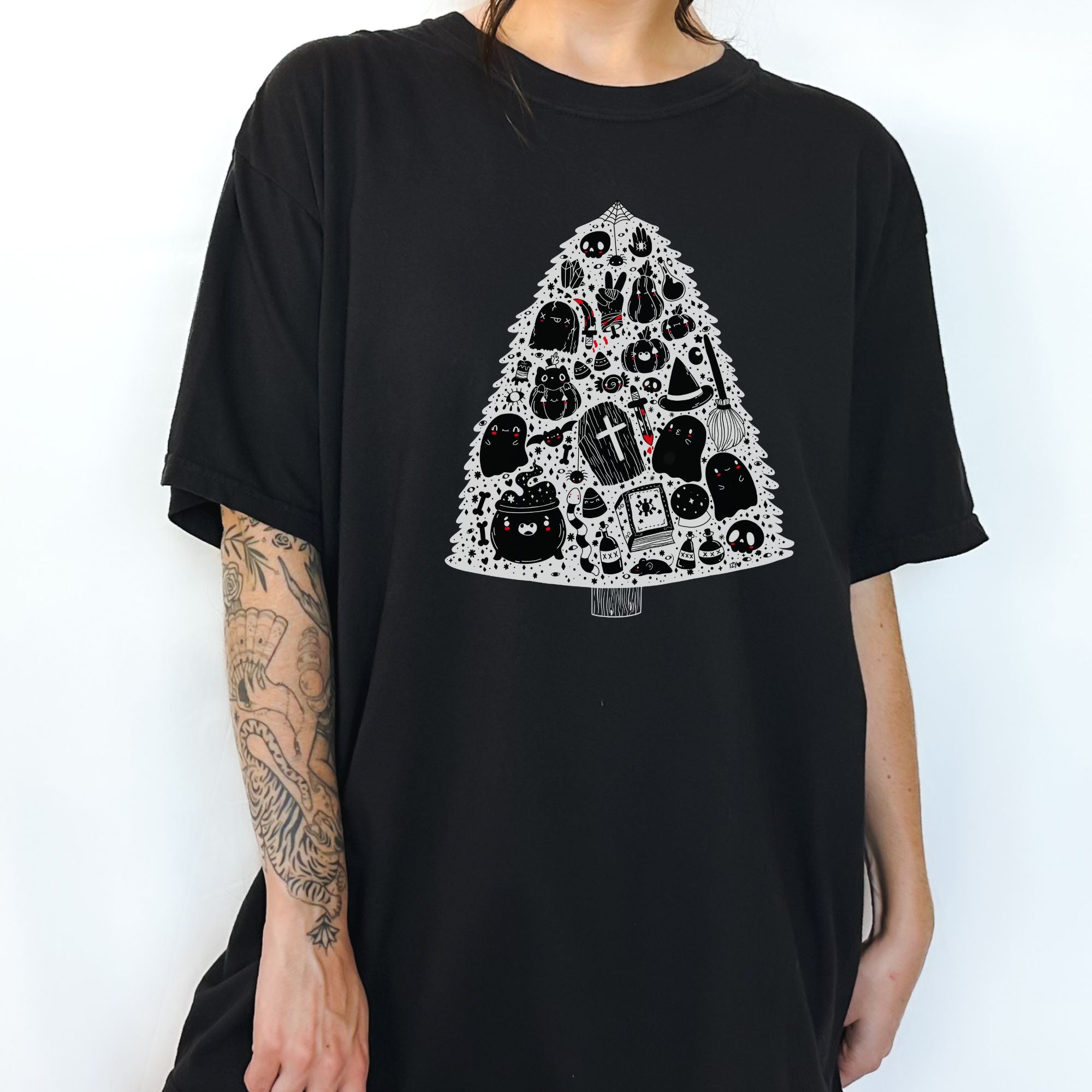 Front view of The Funnel Cake Tree’s black cotton t-shirt featuring a spooky Christmas tree design made up of ghosts, skulls, coffins, cauldrons, and other Halloween icons in white and red artwork.