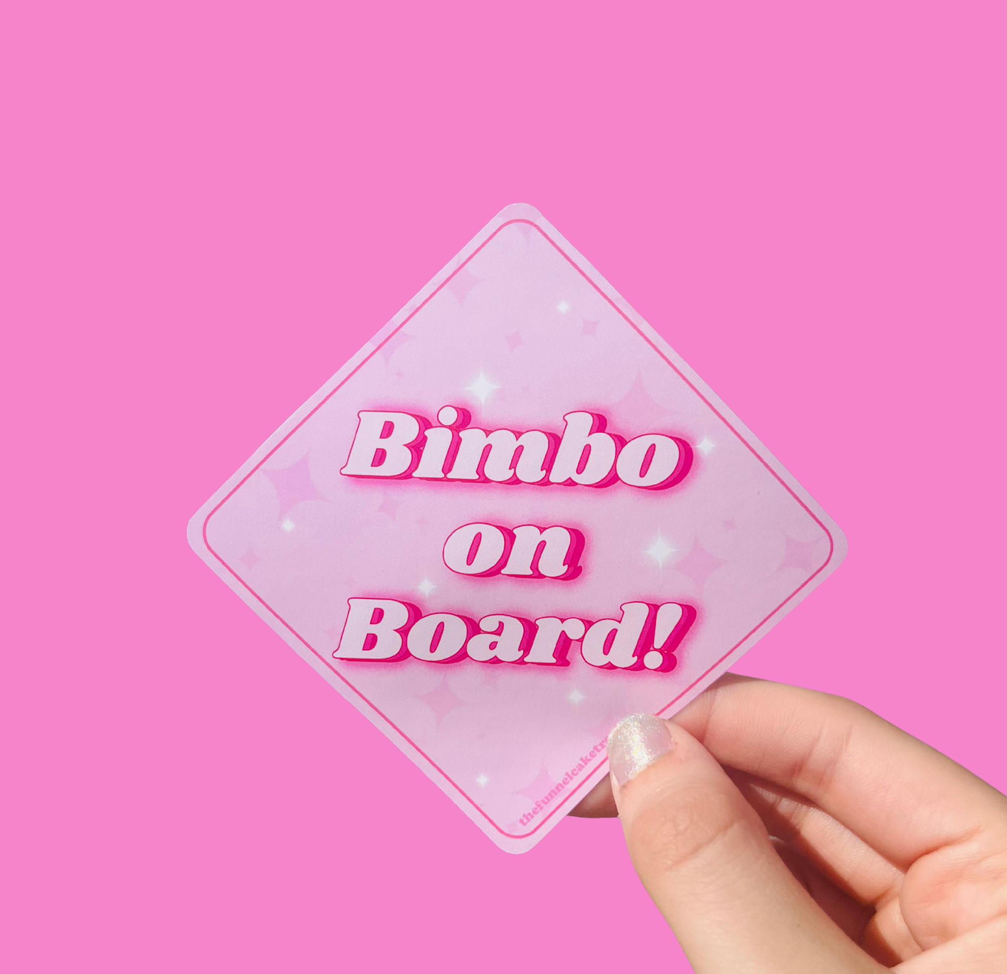 Hand holding a mini bumper sticker reading "bimbo on board." On a solid pink background.