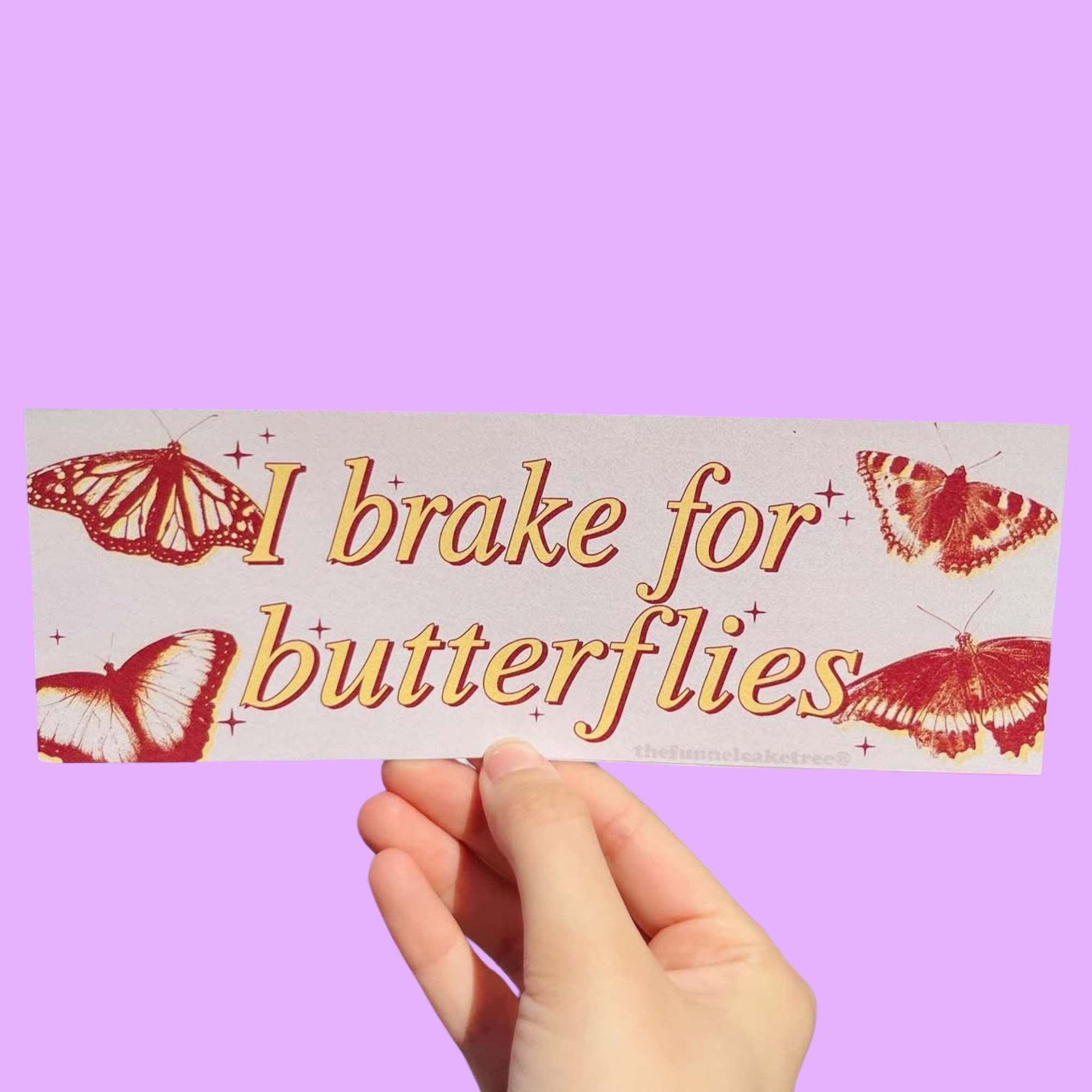  Glossy beige bumper sticker with red and yellow butterflies and text reading “I brake for butterflies.”