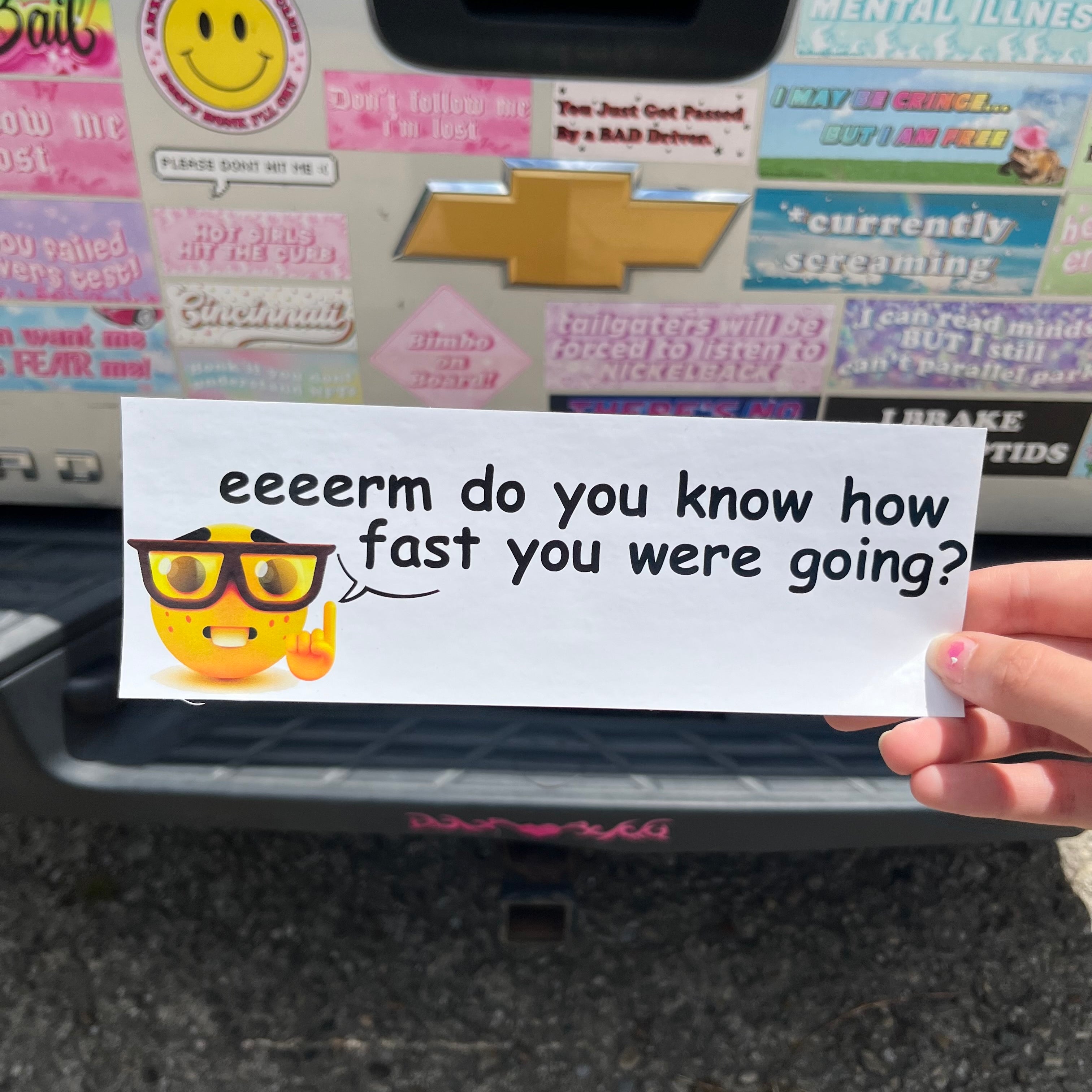 Hand holding a bumper sticker with text eeeerm do you know how fast you were going