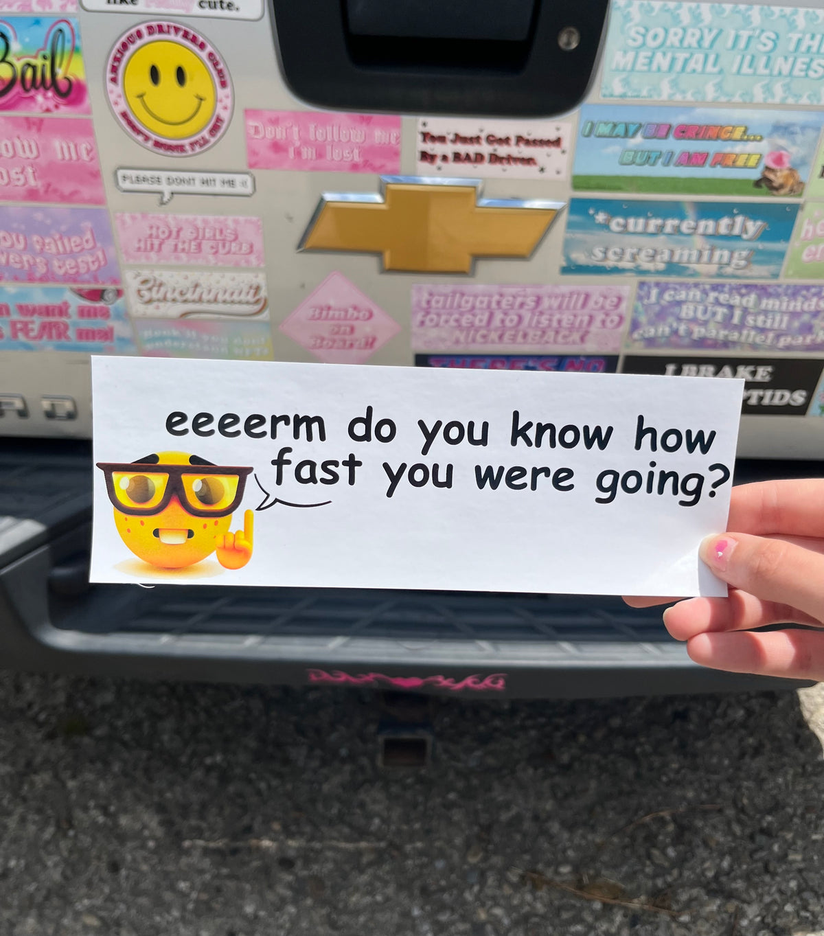 Hand holding a bumper sticker with text eeeerm do you know how fast you were going