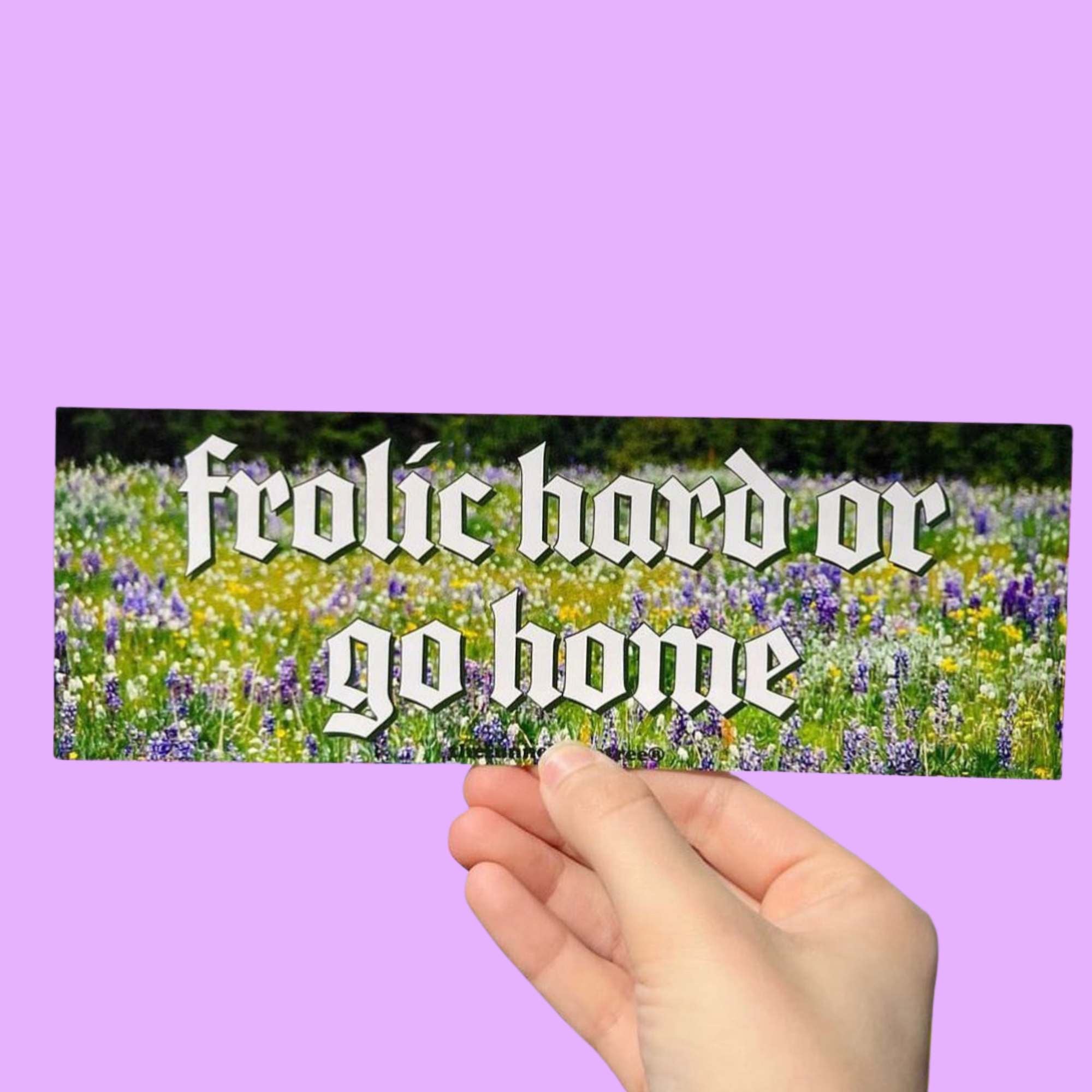  Glossy bumper sticker with gothic white text reading “frolic hard or go home” over a field of colorful wildflowers.