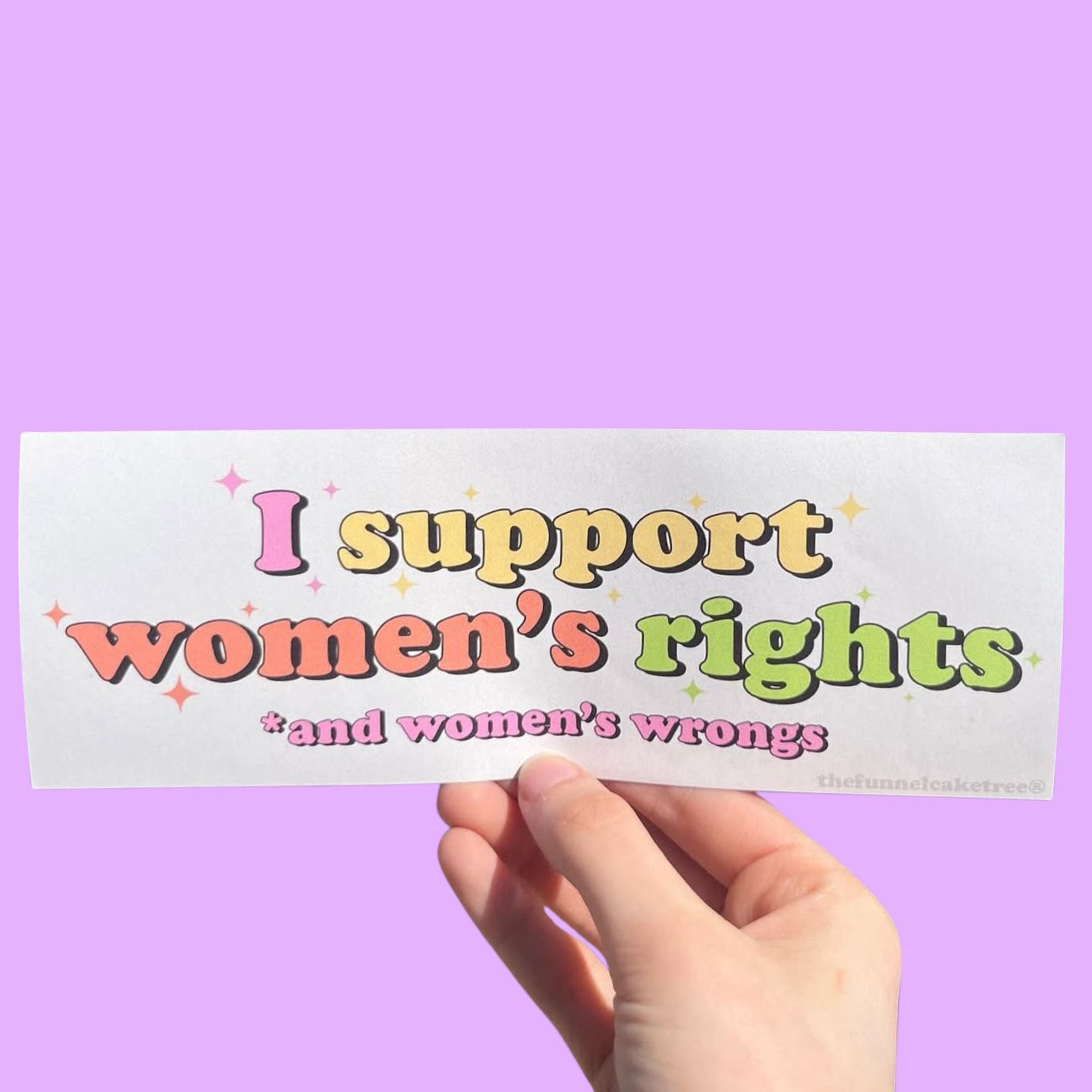  Glossy cream bumper sticker with colorful text reading “I support women’s rights and women’s wrongs” surrounded by sparkles.