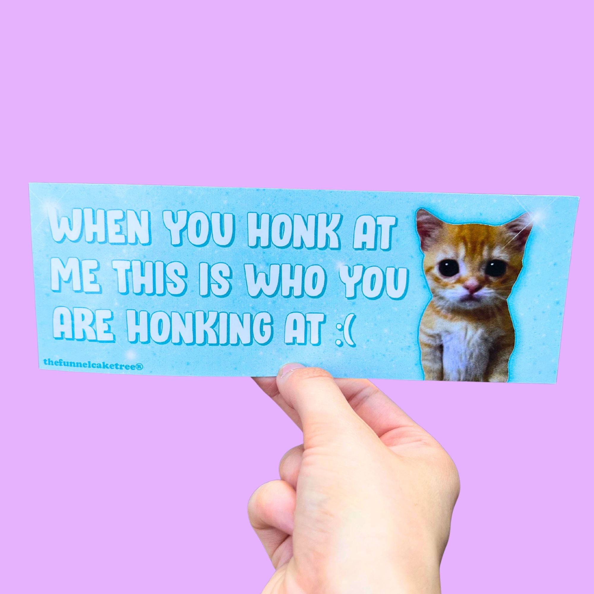 Glossy blue bumper sticker with white text reading “When you honk at me this is who you are honking at :(” next to a sad orange kitten.