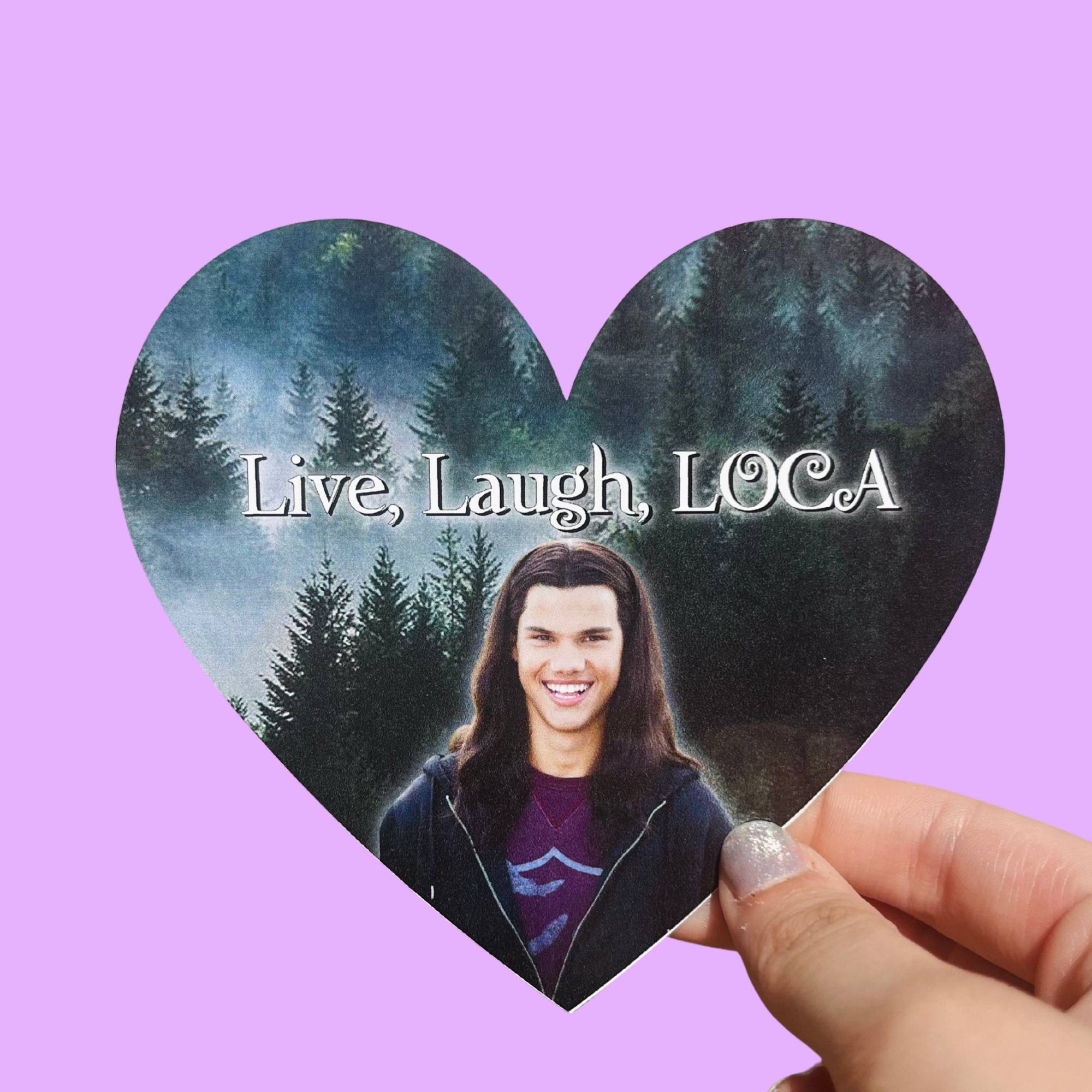 Heart-shaped glossy sticker with a forest background, text reading “Live, Laugh, Loca,” and an image of a smiling character with long brown hair.
