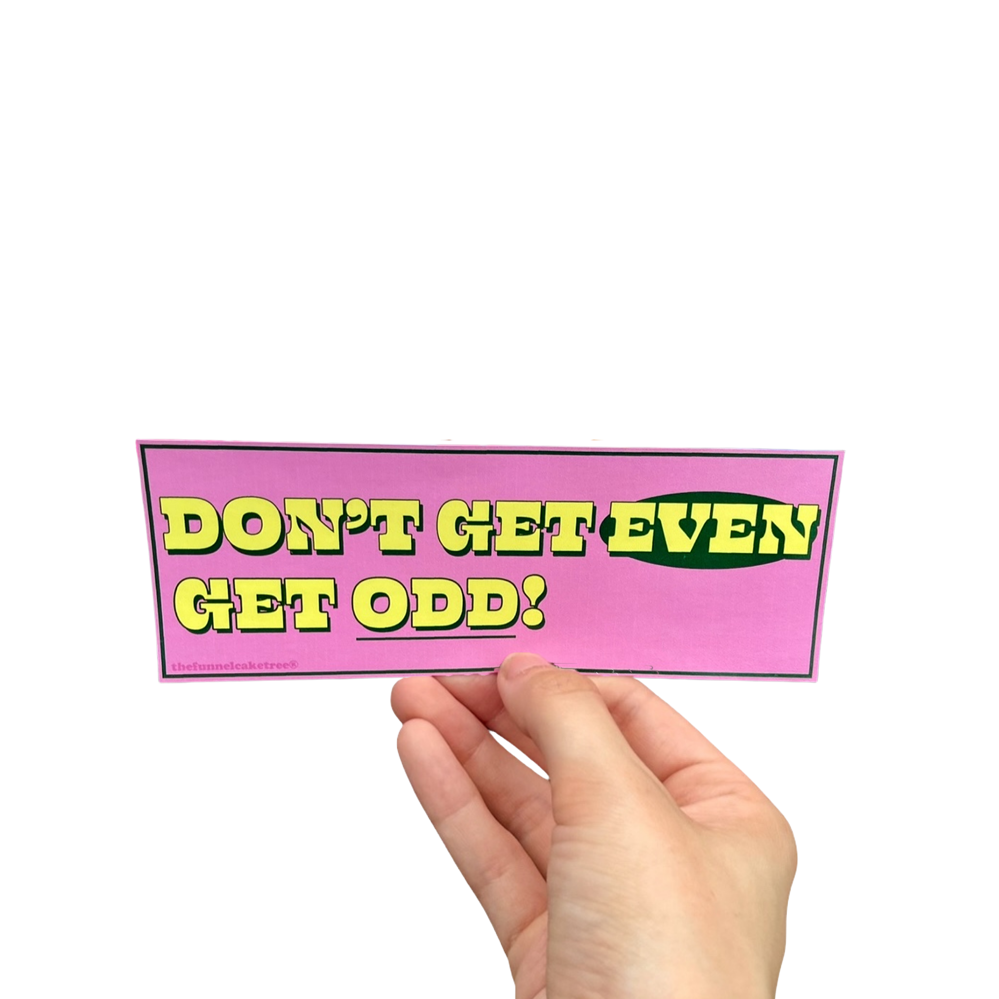 Hand holding a pink mini bumper sticker reading 'Don't get even! Get odd!' in yellow and green lettering.