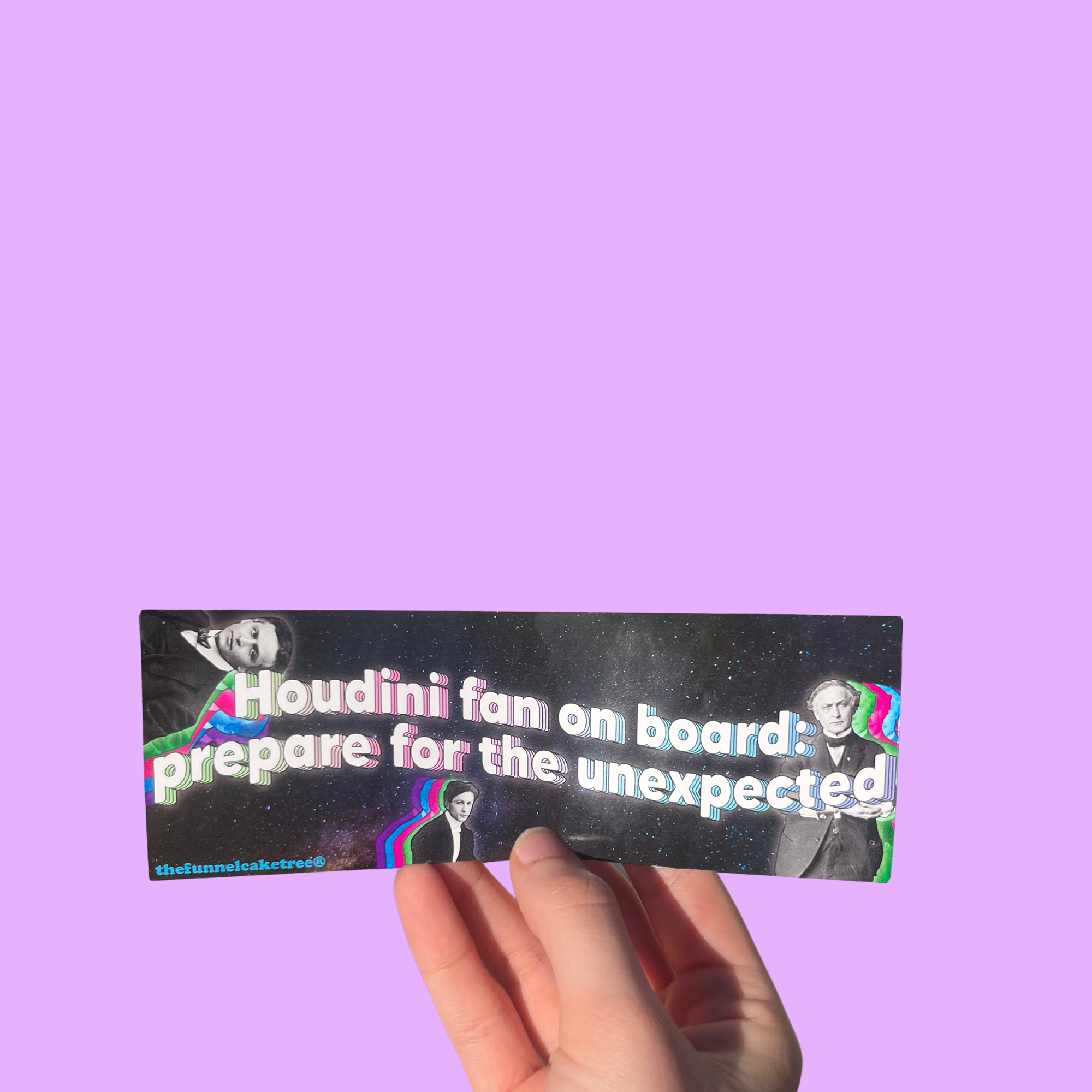 Hand holding a black 'Houdini fan on board: prepare for the unexpected' mini sticker with magician portraits On a solid purple background.