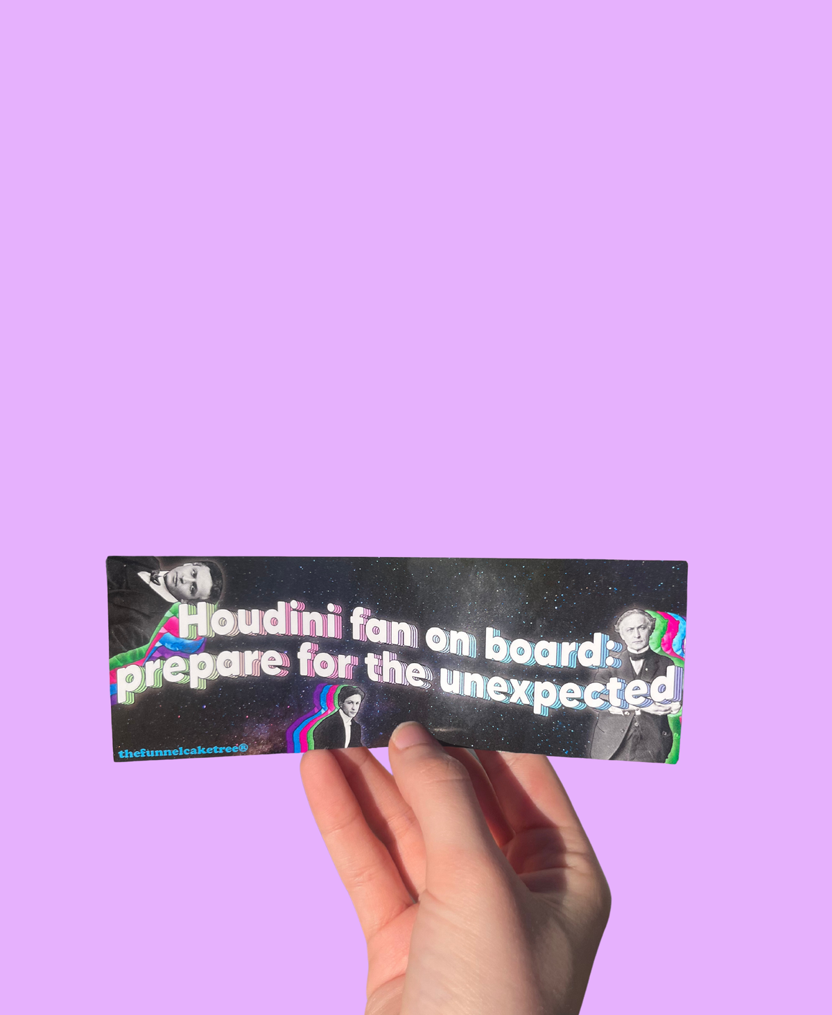 Hand holding a black 'Houdini fan on board: prepare for the unexpected' mini sticker with magician portraits On a solid purple background.