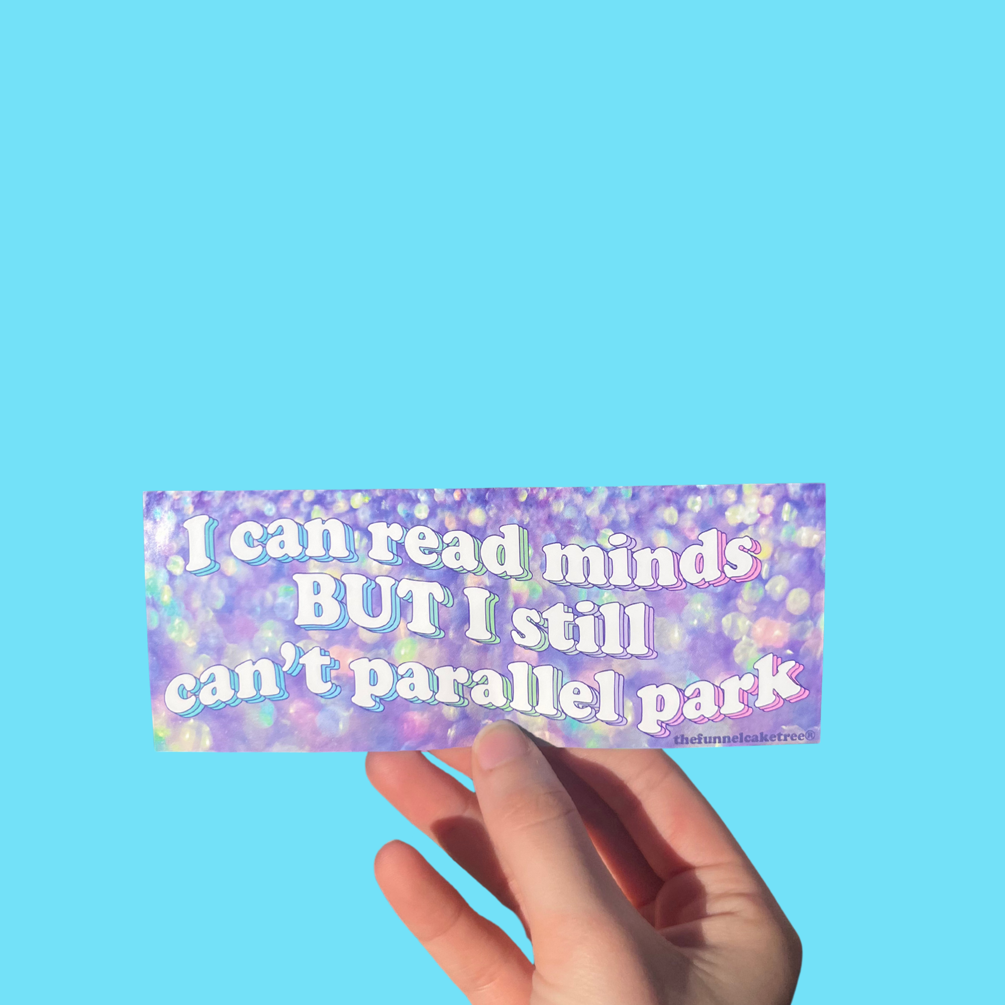 Hand holding a purple iridescent mini bumper sticker reading 'I can read minds BUT I still can't parallel park' On a solid teal background.