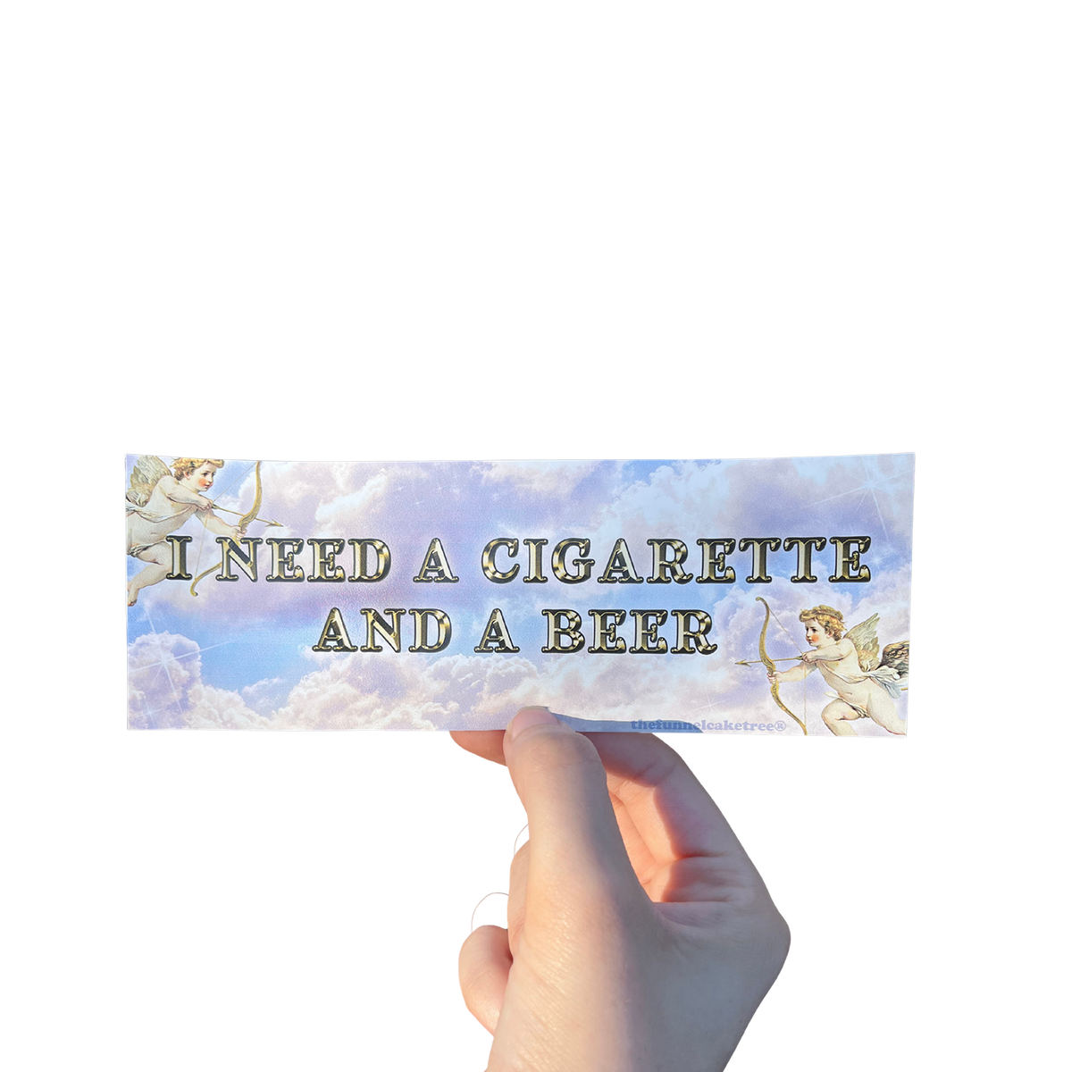 Hand holding a cloudy mini bumper sticker reading 'I NEED A CIGARETTE AND A BEER' beside a cherub illustration.