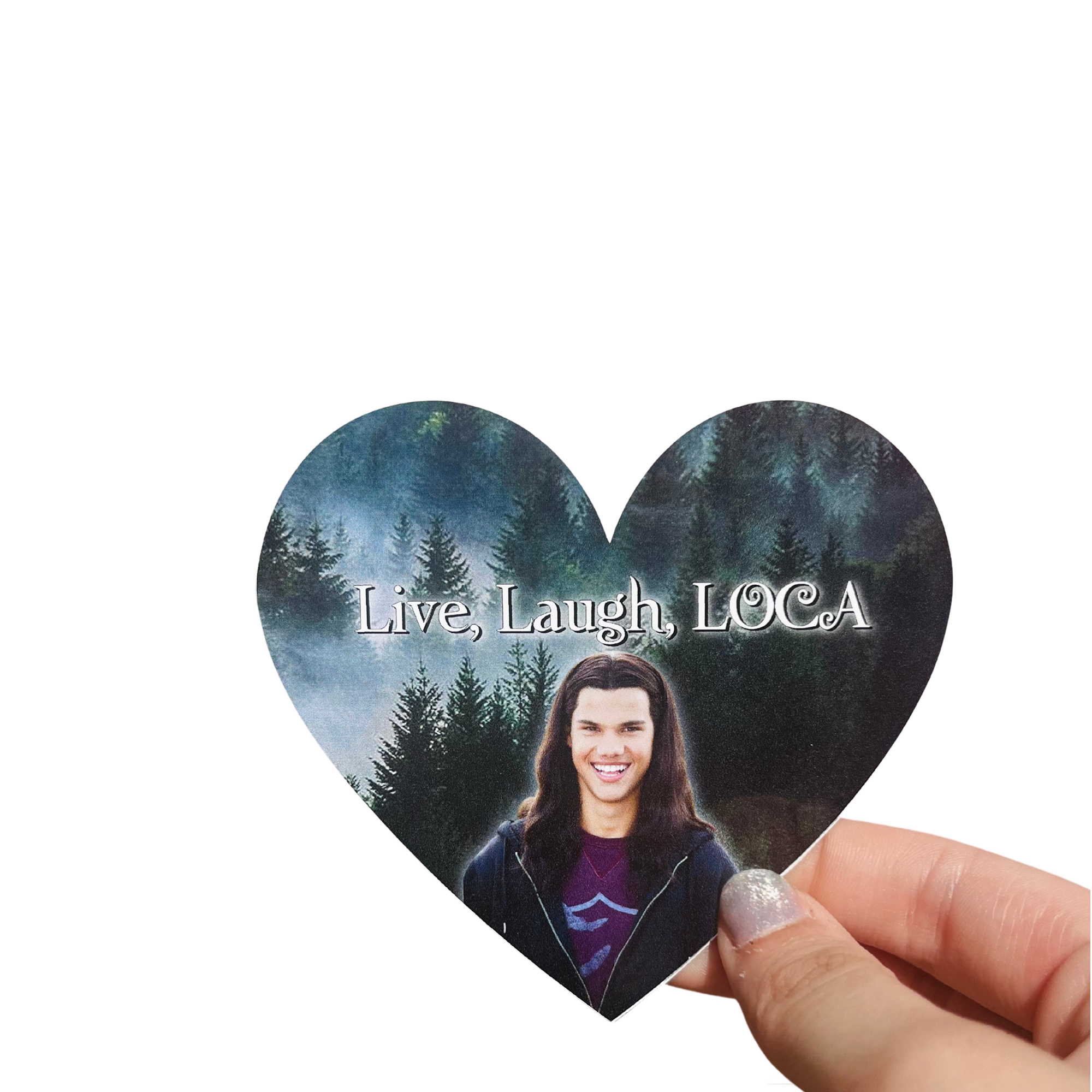 Hand holding a heart-shaped 'Live, Laugh, LOCA' sticker with a long-haired man's portrait and a forest background.