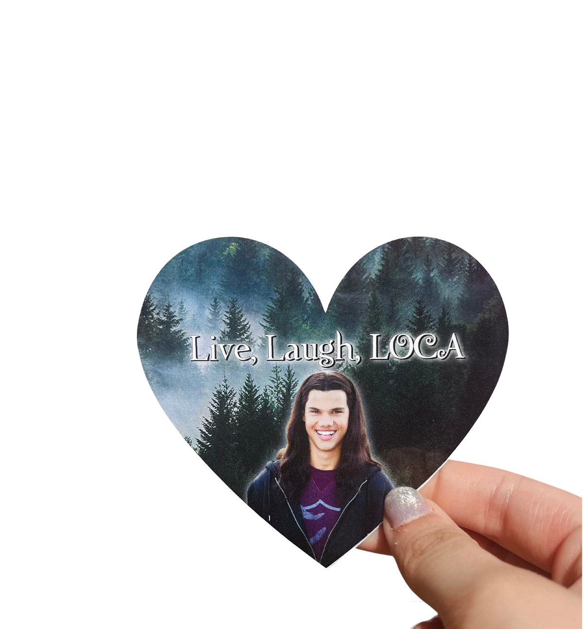 Hand holding a heart-shaped 'Live, Laugh, LOCA' sticker with a long-haired man's portrait and a forest background.