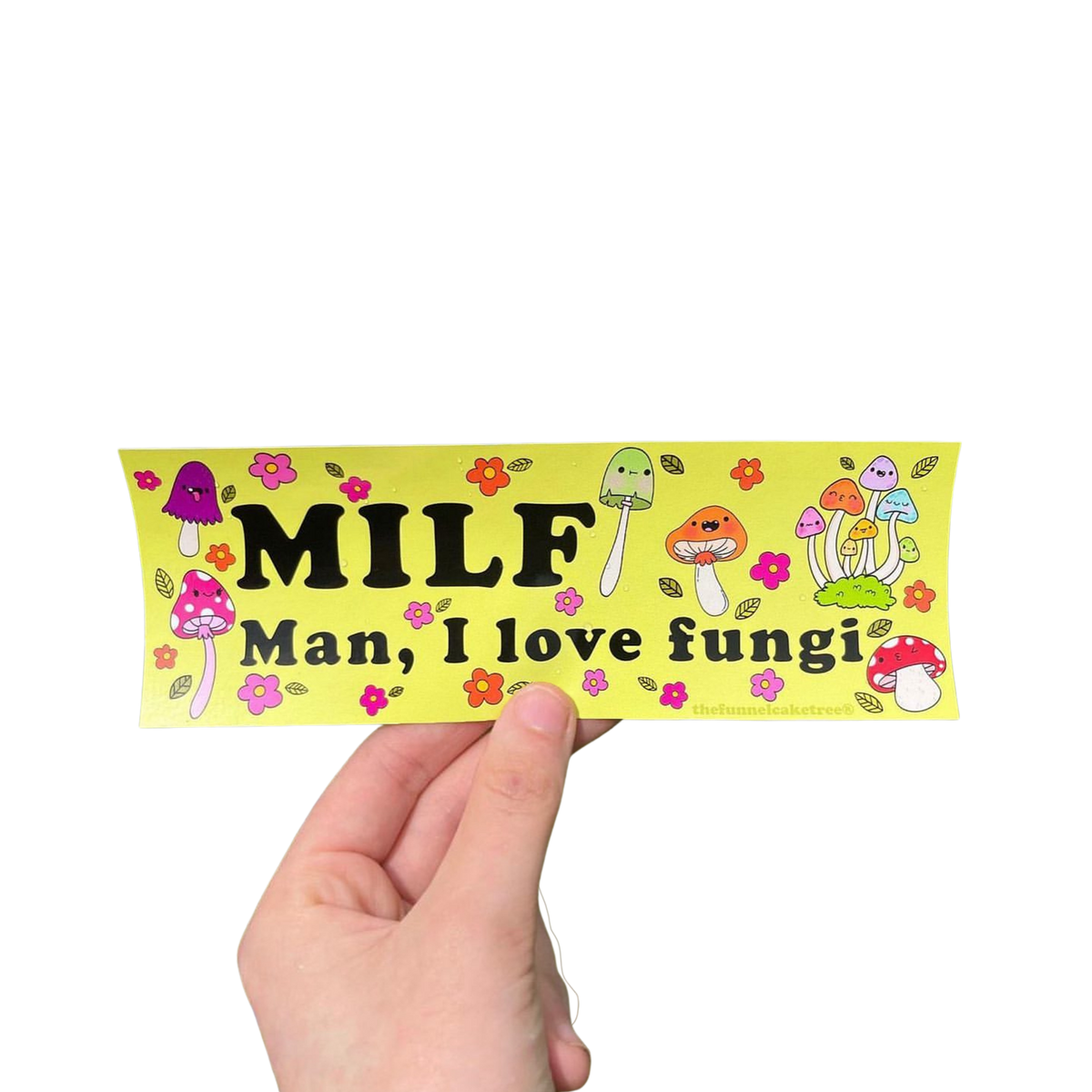 Hand holding a yellow-green 'MILF — Man, I love fungi' mini bumper sticker with colorful mushrooms and flowers.