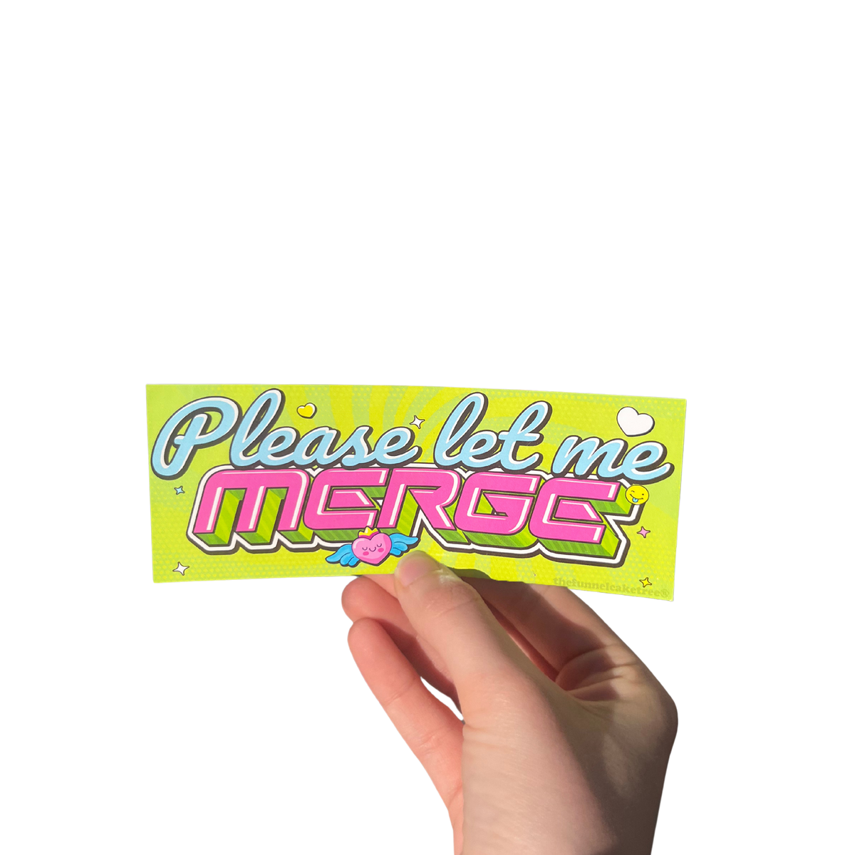 Hand holding a lime green Y2K-style mini bumper sticker reading 'Please let me MERGE' in pink and white letters.