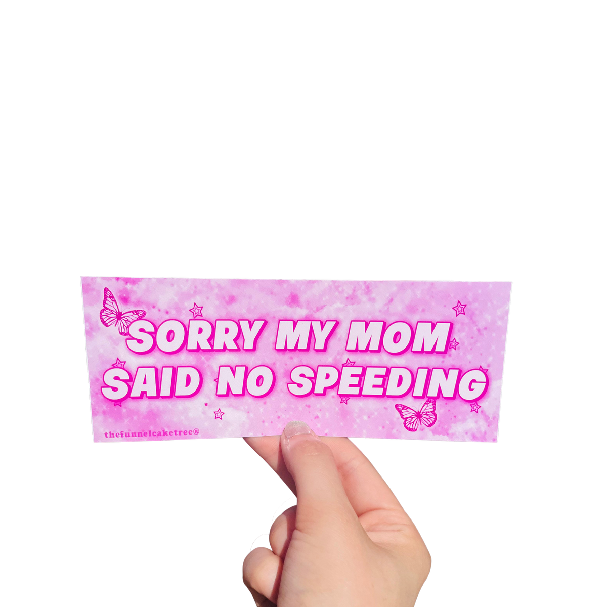 Hand holding a hot-pink mini bumper sticker reading 'Sorry my mom said no speeding' with butterflies and stars.