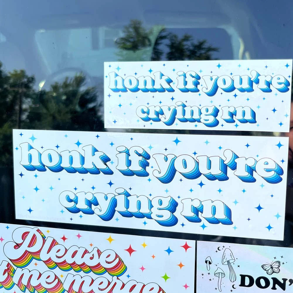 Mini and full-size Honk If You're Crying bumper stickers shown together on a car window for size comparison.