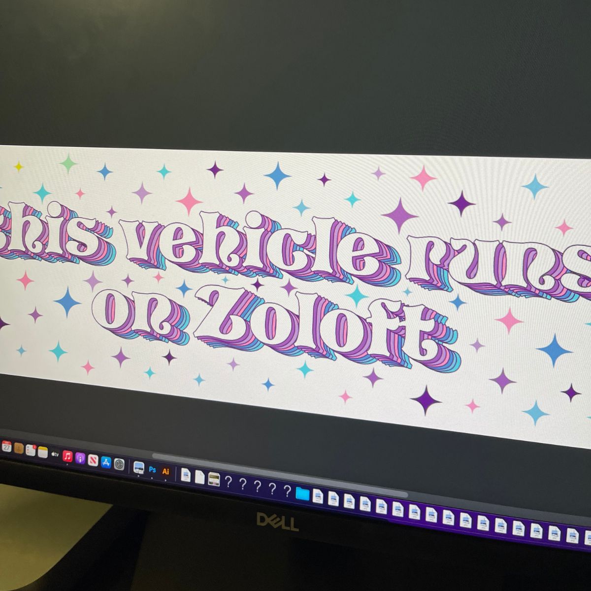 Glossy white bumper sticker with pastel rainbow text reading “This vehicle runs on Zoloft,” surrounded by colorful starburst accents.