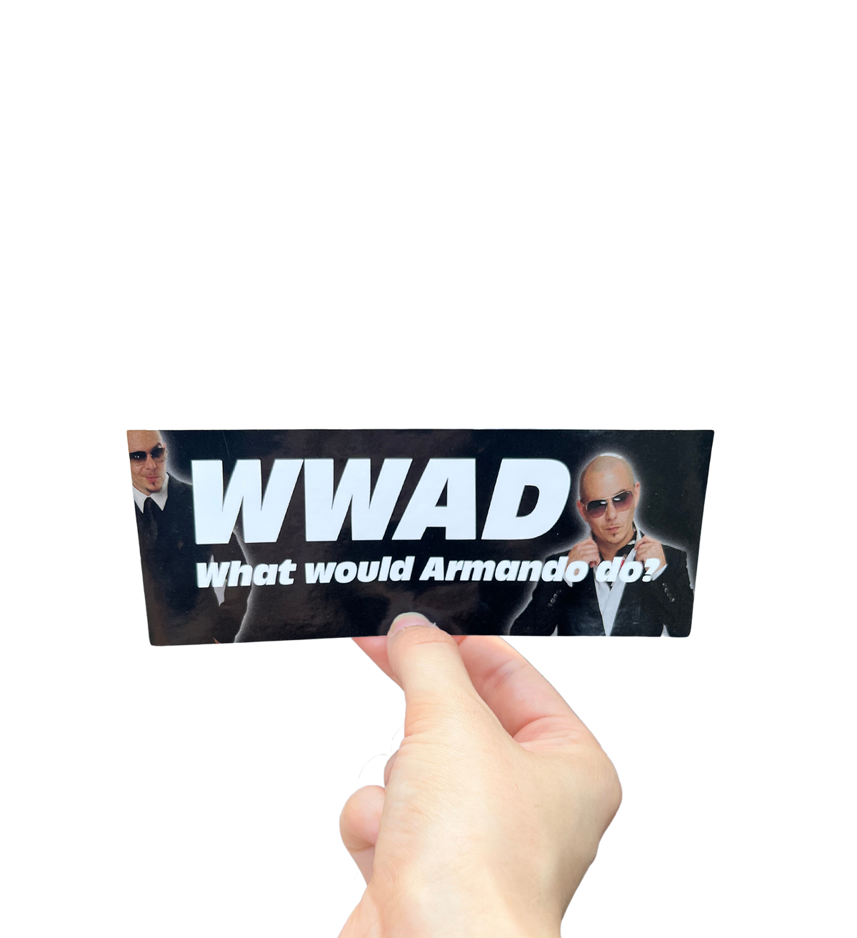 Hand holding a black mini bumper sticker reading 'WWAD — What would Armando do?' with portraits of a man in sunglasses.