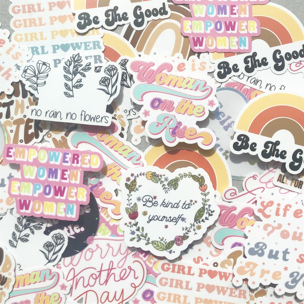 Assorted colorful paper stickers featuring rainbows, flowers, and text like Be the Good and Empowered Women Empower Women.