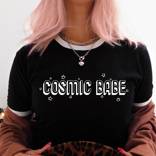 The Funnel Cake Tree “Cosmic Babe” black ringer tee featuring bold white block lettering with stars. A retro-inspired graphic shirt for celestial and space-loving babes.