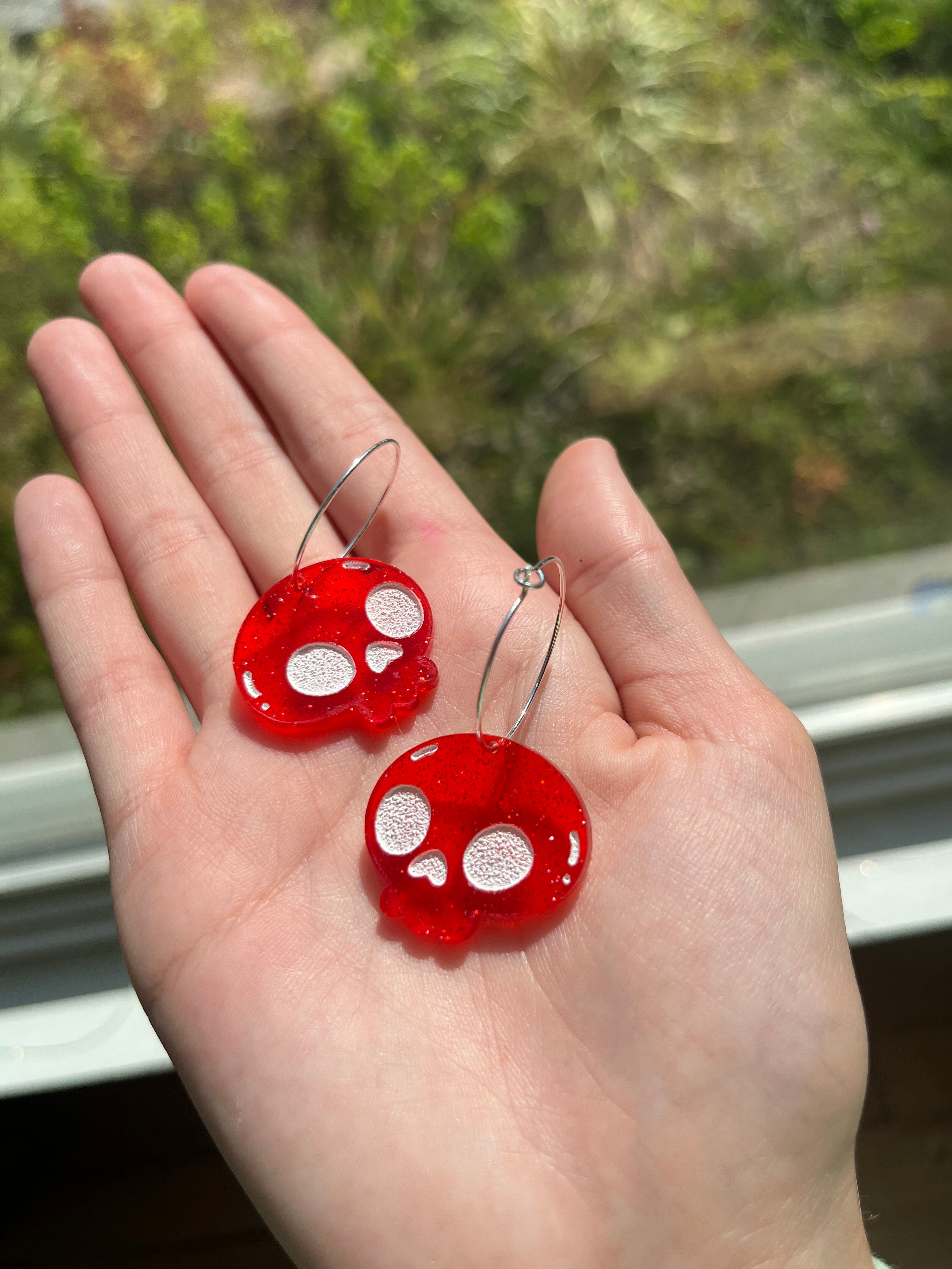 Isabel holding red skull acrylic earrings 