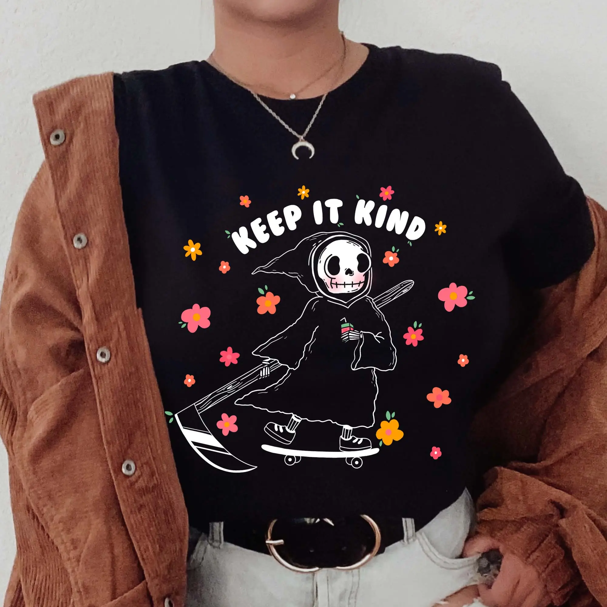 Woman wearing a black tshirt decorated with the hand drawn keep it kind art from izzy with the funnel cake tree 