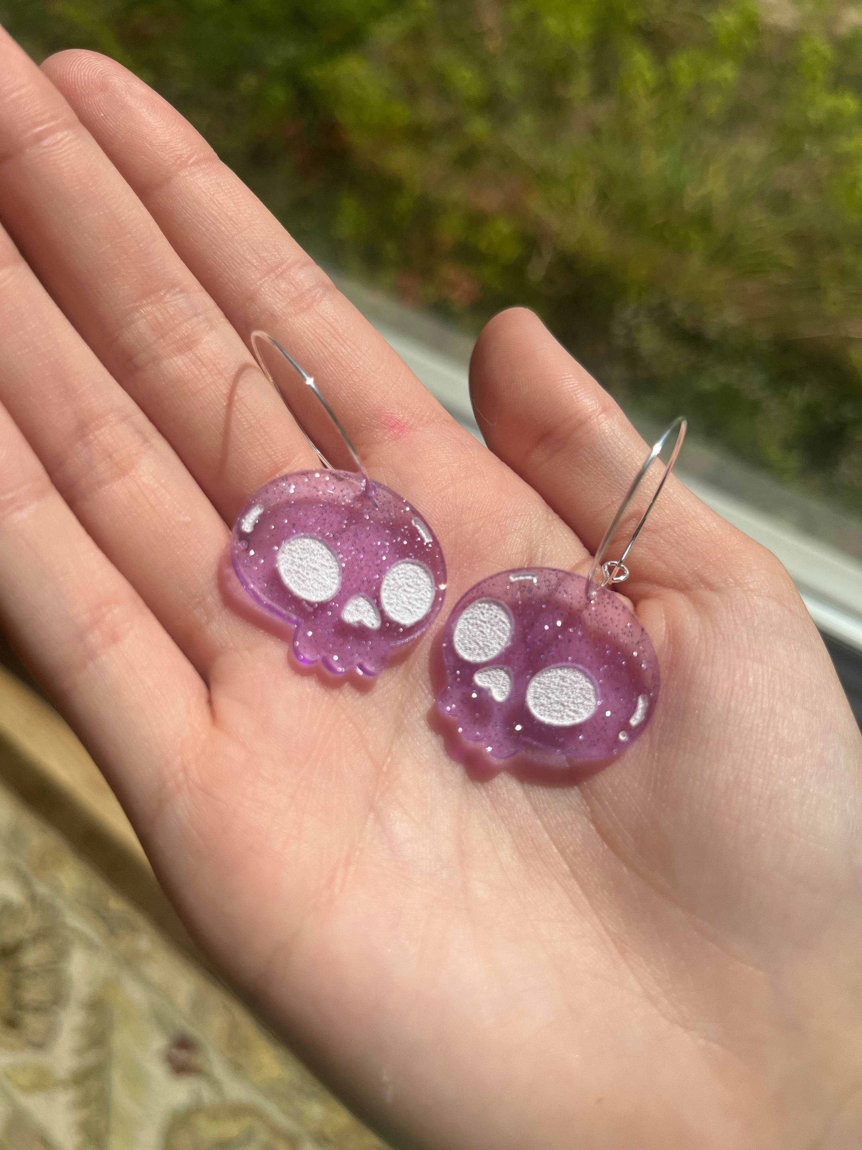 Isabel of The Funnel Cake Tree holding purple skull acrylic earrings 