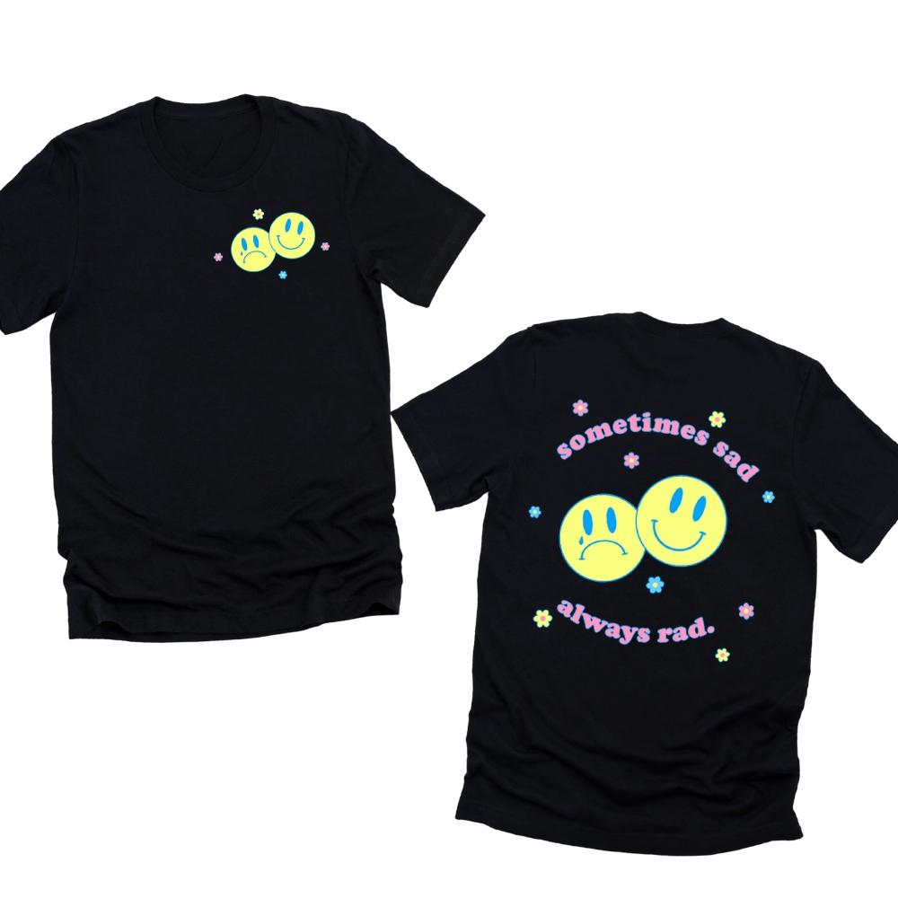Black graphic t-shirt featuring two yellow smiley faces with pastel flowers and pink retro text “Sometimes Sad Always Rad” printed on the front and back – The Funnel Cake Tree.