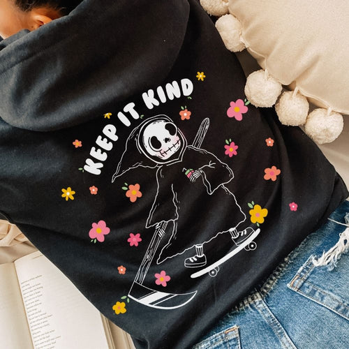 Black fabric hoodie with a grim reaper on a skateboard surrounded by flowers and the text Keep it Kind.