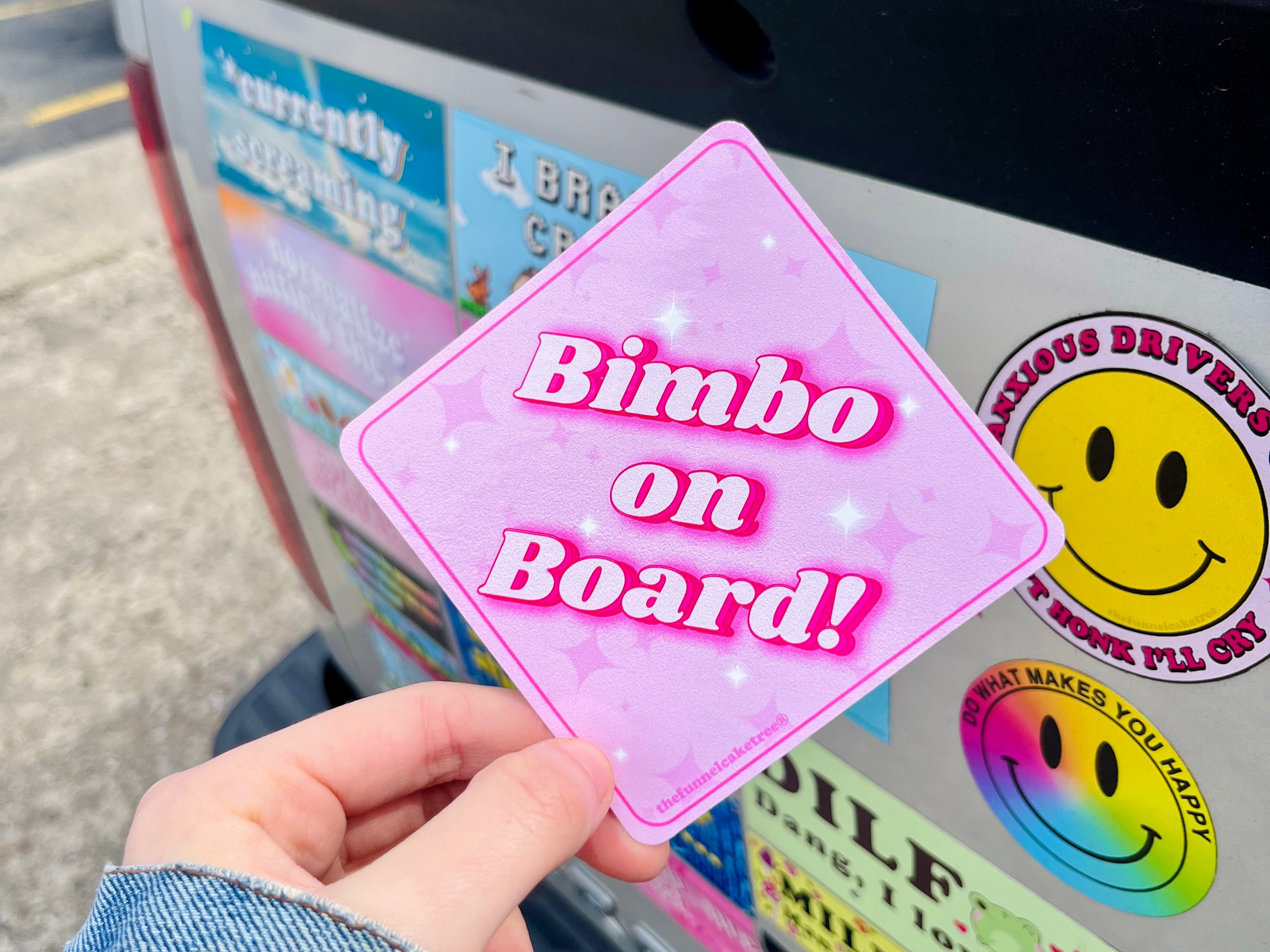 izzy from the funnel cake tree holding a diamond shaped pink sticker that says bimbo on board