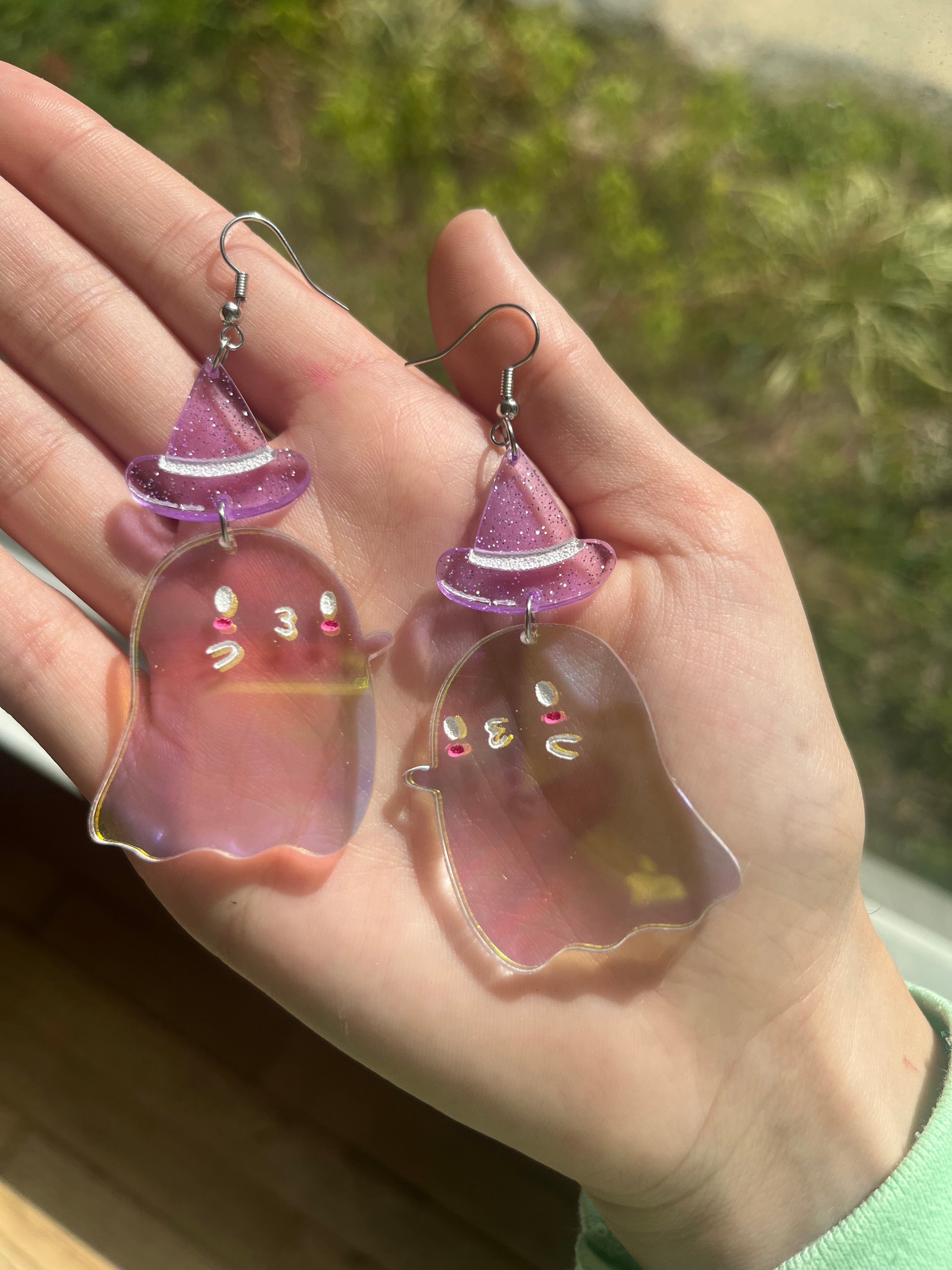 Izy from The Funnel Cake Tree holding a pair of ghost shaped dangle earrings in her hand