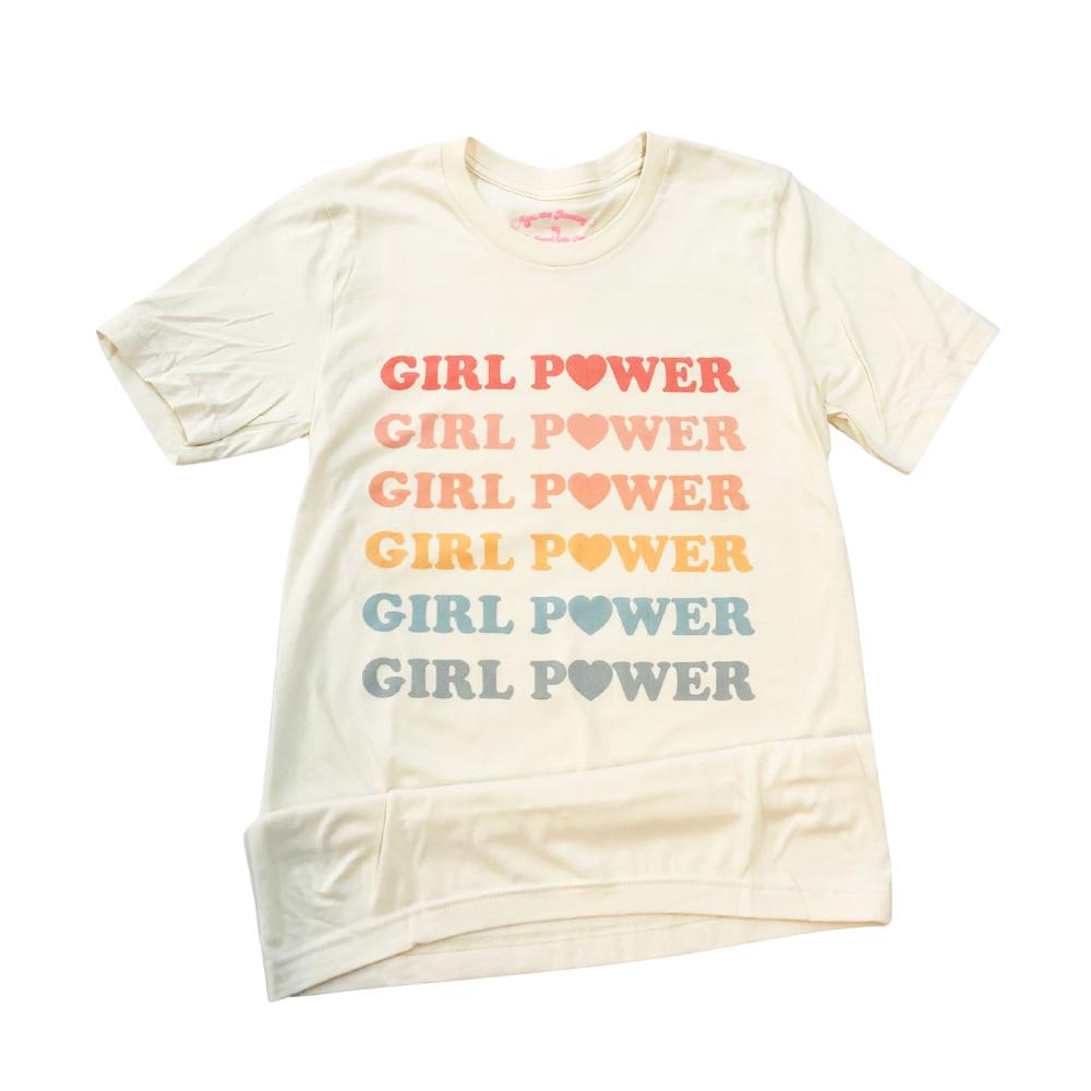 Cream-colored graphic tee featuring repeated ‘Girl Power’ text in pastel rainbow colors with heart icons, flat lay style, designed by Funnel Cake Tree.