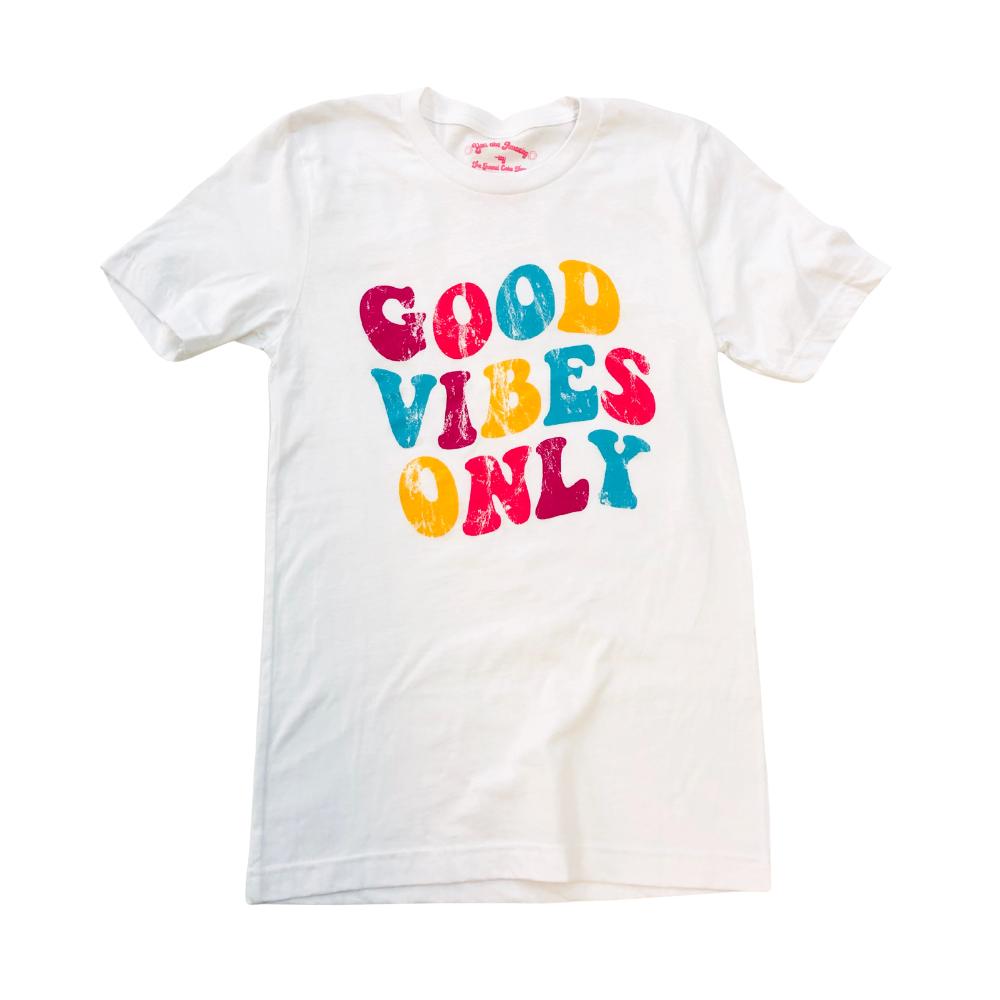 Flat lay of white ‘Good Vibes Only’ graphic tee by Funnel Cake Tree featuring colorful retro lettering in pink, yellow, and teal  positive energy shirt for everyday wear.