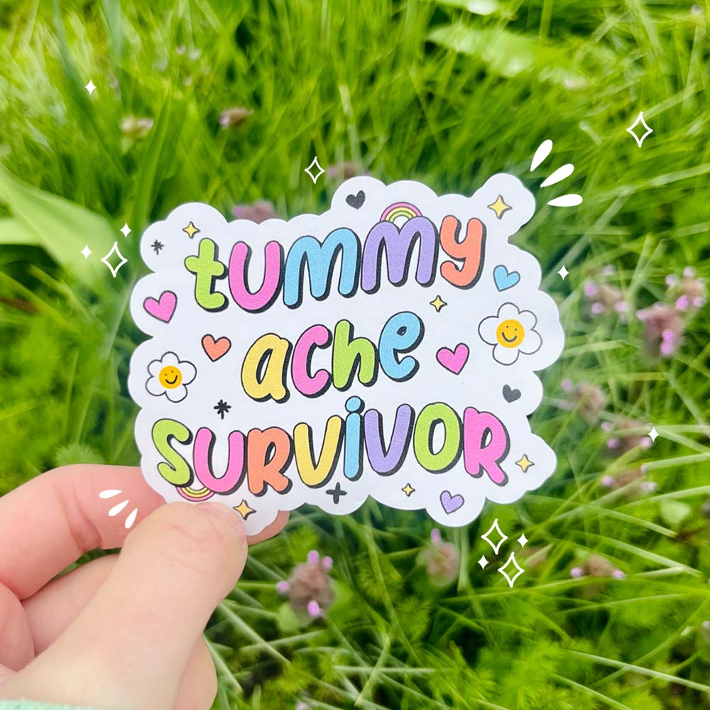 Pastel rainbow die-cut vinyl sticker reading “Tummy Ache Survivor” with hearts, stars, and smiley daisies.