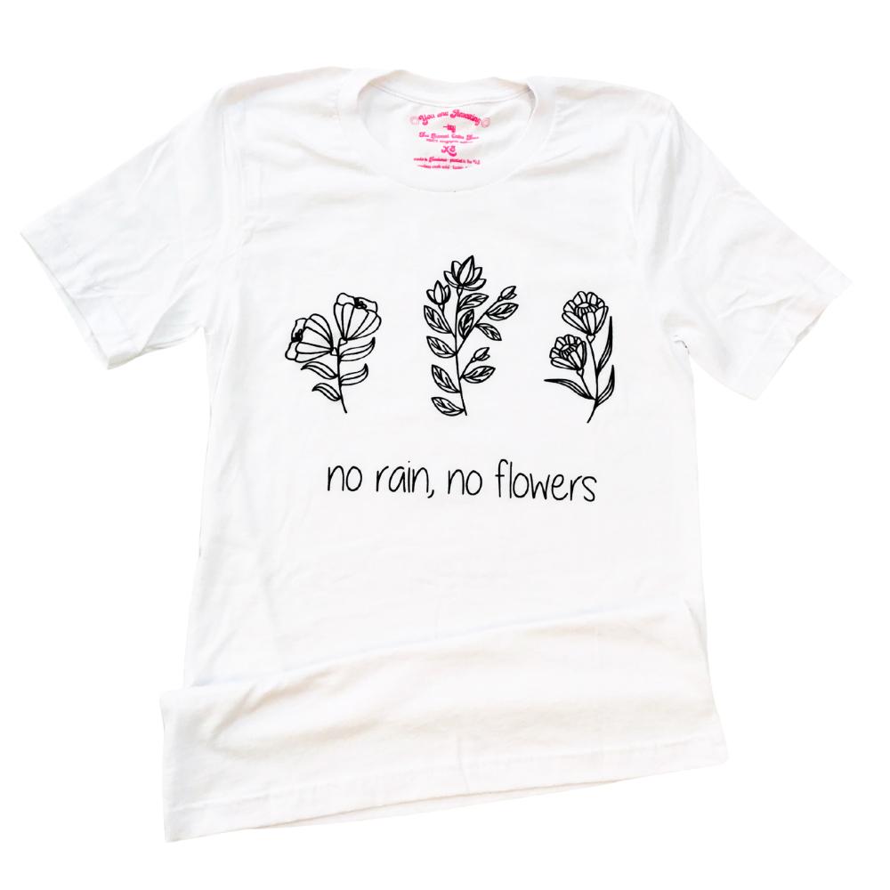 White t-shirt with black line art flowers and the words ‘no rain, no flowers’ printed across the front in minimalist script.