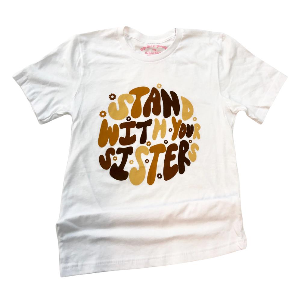 Stand With Your Sisters flat lay graphic tee by Funnel Cake Tree white unisex t-shirt with retro brown and gold lettering and small flower accents displayed on a flat surface.