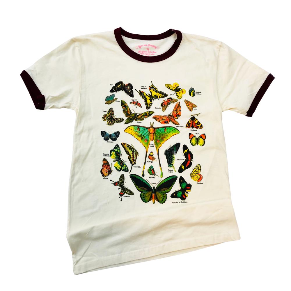 Flat lay of a vintage-style cream ringer t-shirt with burgundy trim featuring colorful butterfly and moth illustrations.