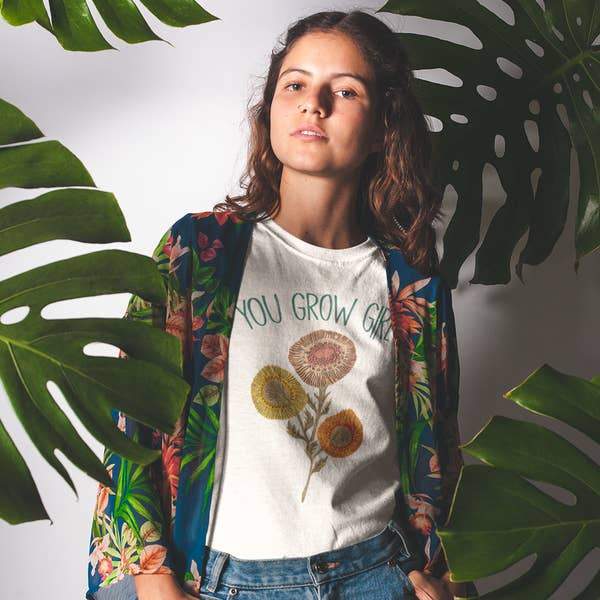 Woman wearing a cream ‘You Grow Girl’ graphic tee with colorful retro floral design, styled with jeans and a patterned kimono  empowering botanical shirt for women.